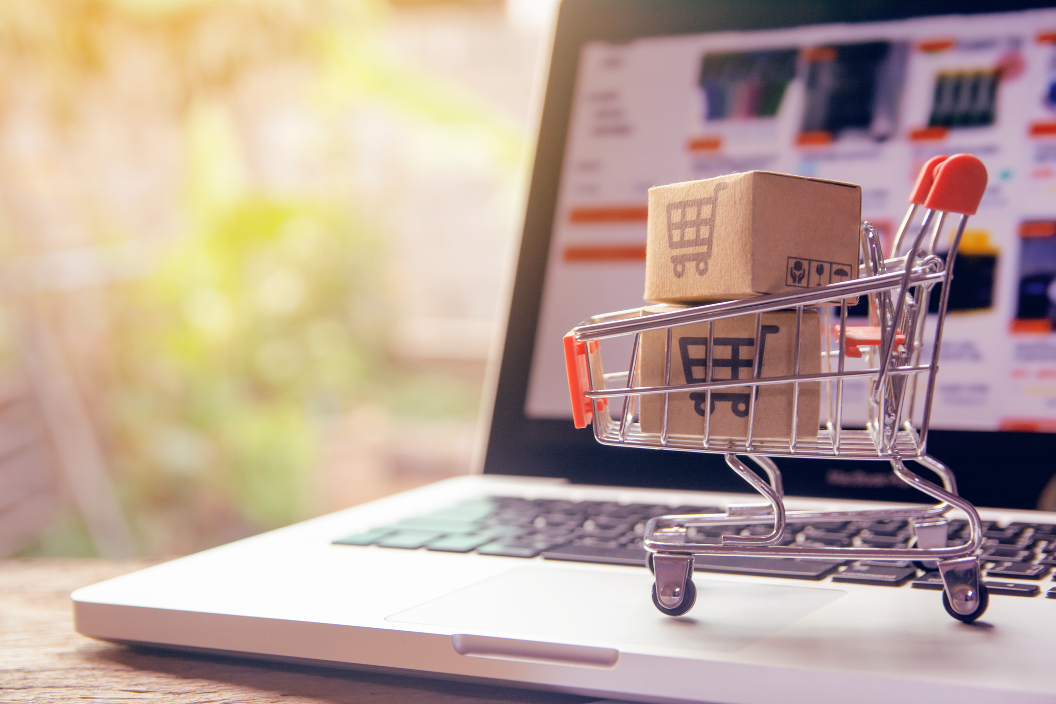 Panier d'achat avec des colis sur un ordinateur, représentant le développement de sites web et d'e-commerce.